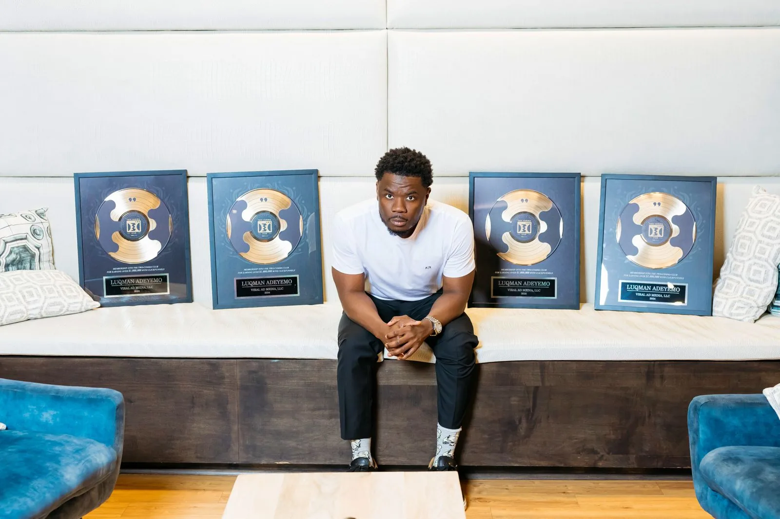 Luqman seated beside four framed industry awards